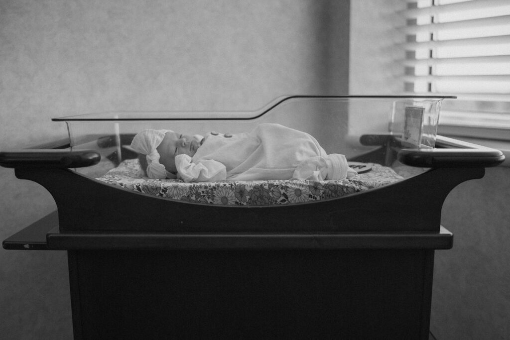 Newborn baby is laying in the hospital bassinet for a fresh 48 session, included in the family milestones collection.